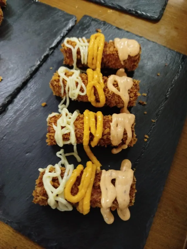 Croquetas variadas sobre pizarra con salsas