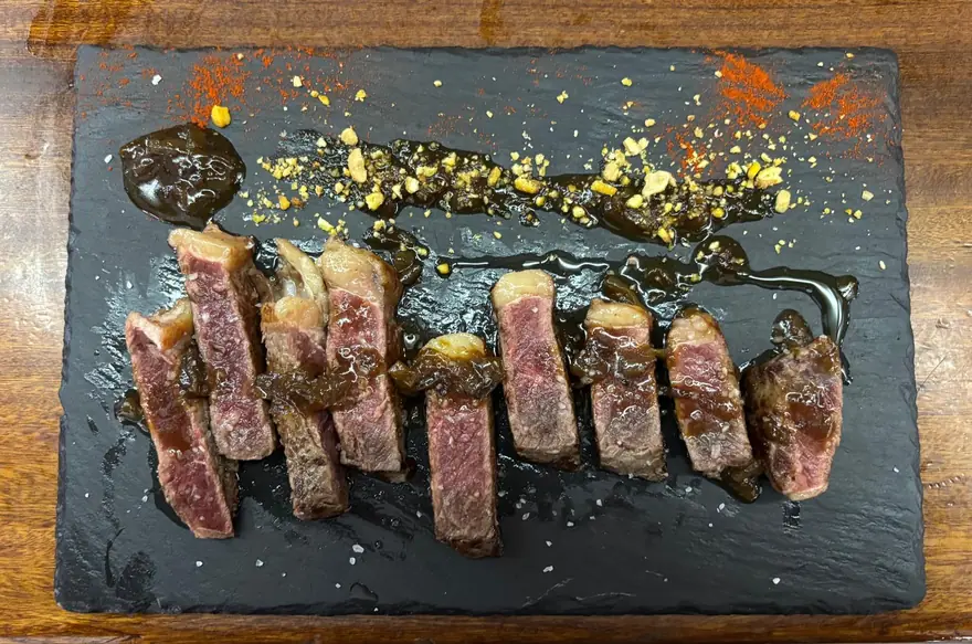 Tataki de vaca madurada cortado en láminas sobre pizarra